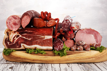 cold meat assortment with delicious salami and  fresh herbs . Variety of meat products including proscuitto, jamon  and sausages