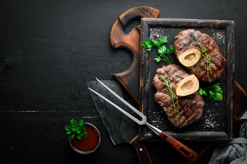 Beef shank roasted on a grill on a wooden background. Top view. Free space for your text.