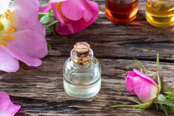 A bottle of essential oil with dog rose flowers
