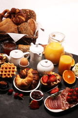 Huge healthy breakfast on table with coffee, orange juice, fruits, waffles and croissants. Good morning concept.