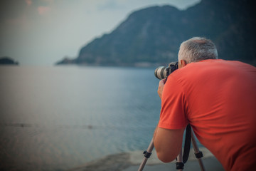 Obraz premium the photographer takes a photo on the sea in the mountains