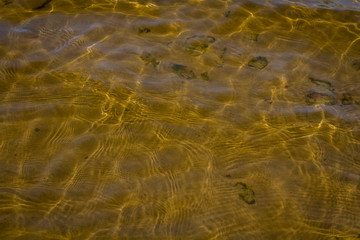 the sand and stones under water with the waves in the foreground .