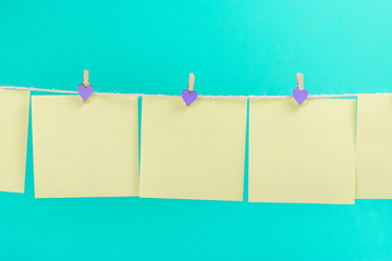 Green stickers on clothesline with clothespins isolated on blue background. Place for your text.