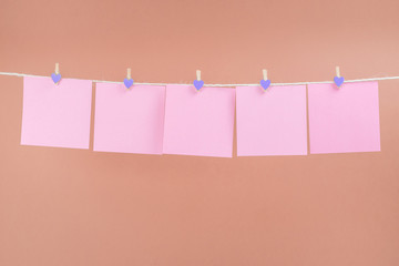 Pink stickers on clothesline with clothespins isolated on brown background. Place for your text.