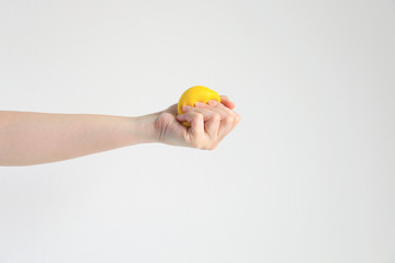 Hand pressing yellow squishy ball for exercise muscle or for feeling relax from stress; concept of health care and medical.