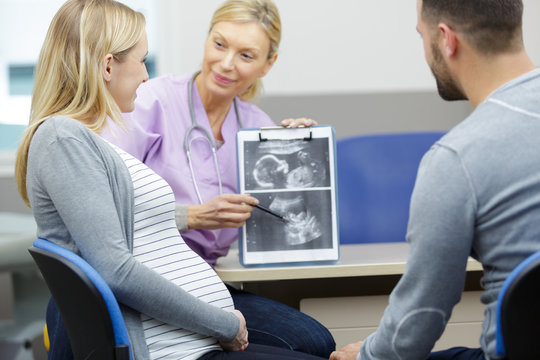 handsome male doctor shows ultrasound to pregnant couple