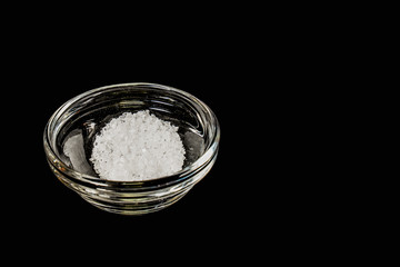 A pinch of salt in a small, bowl on a black background.