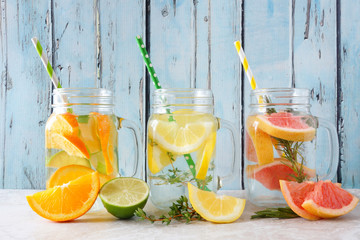 Variety of citrus infused detox water drinks in mason jar glasses against a blue wood background