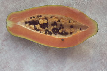 Papaya (Carica papaya) is an exotic, tasty, sweet fruit. Melon (bread) tree fruit against a pink background. Half. Papaya seeds are edible and can be a cure. Close-up.