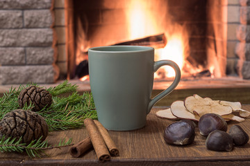 Cozy scene near fireplace with mug of hot tea, warm scarf and candles.