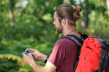 man with backpack looking at direction on compass