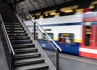 Fahrender Zug der an einer leeren Treppe vorbei f&auml;hrt