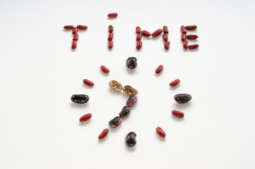 Word time and clock face shaped out of colorful kidney beans on white background. Healthy eating concept. Time to eat legumes