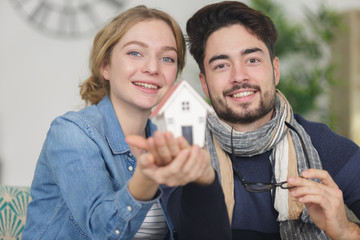 couple holding a model house in their hands