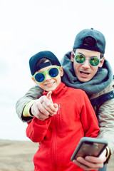 young father with his son having fun outside in spring field, happy family smiling, lifestyle people making selfie wearing sunglasses