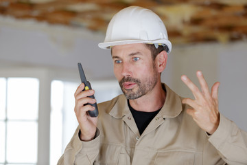 male builder in hardhat with walkie talkie