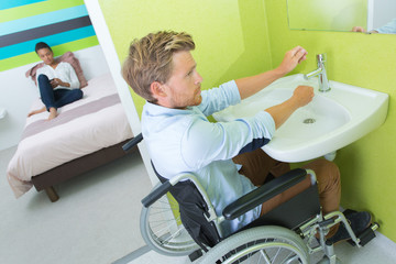 Obraz premium man on wheelchair washing hands in bathroom
