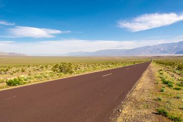 Trona Wildrose Road that leads to the Death Valley in California on a beautiful sunny day with blue sky and mountains in the background.