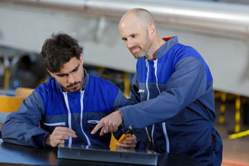 mechanic giving instructions to his apprentice