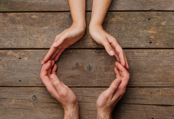 Male and female hands on rustic wooden background with copy space