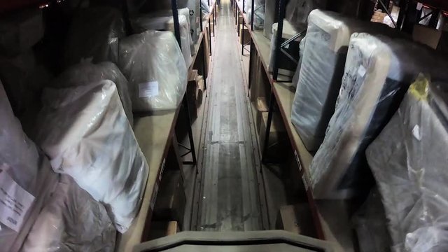 Stunning point of view shot from a forklift constantly working in a large storage warehouse.