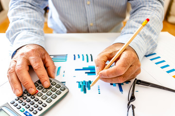 Man using calculator and writing on a notepad.