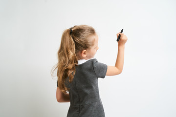 Little girl photographed against white background wearing school uniform dress isolated is mocking...