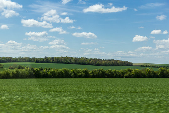 Countryside landscape with blue sky in Northern France. View from car window with blurred field
