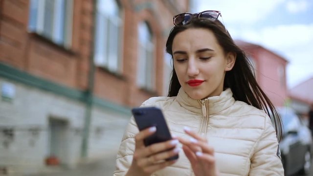 Surprised young woman using smart phone outdoors.
