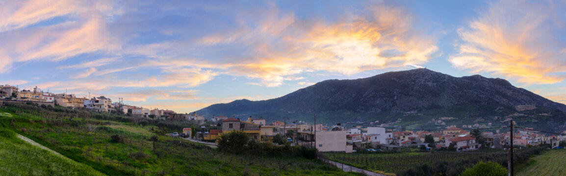 Archanes, Crete Island / Greece. Panoramic view of Archanes town at sunset time. Sun has just went down behind Juktas mountain giving to the cloudy sky beautiful colors