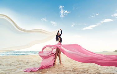 Slim Woman at the beach with long pink fabric. Sky background at the summer. Classic dancer on the...