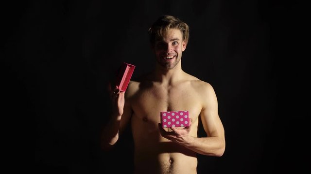 Sexy man with a gift box isolated on black background. Macho torso man hold and open gift box. Present for you. Valentines day concept. Attractive man with pink box. Man with romantic gift.
