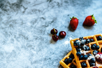 Close-up of a waffle with blueberries and strawberries with delicious aspect, isolated on abstract background with copy space for text.