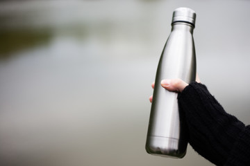 Close-up of steel thermo bottle in hand of young girl