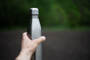 Stainless thermos bottle in man hand
