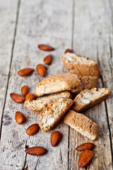 Fresh homemade Italian cookies cantuccini heap and almond nuts on ructic wooden table.