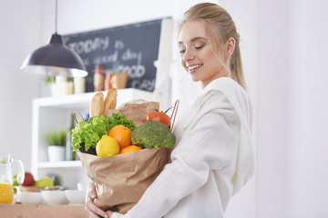 Young woman holding grocery shopping bag with vegetables Standi