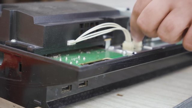 A specialist cleans the game console board from dust with a brush