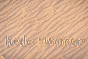 Fototapeta na wymiar The inscription on the sand. Hello summer. Concept of beach season. Postcard. Shadows on the sand.