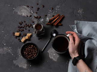 Fototapeta na wymiar hand take cup of coffee dark background beans top view espresso cinnamon