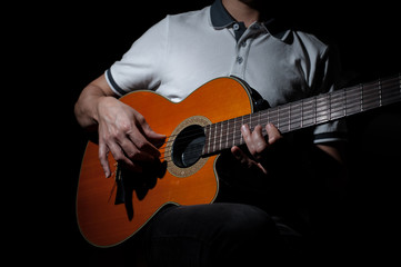 Obraz na płótnie Canvas Man playing an acoustic guitar on a dark background. Playing guitar