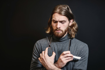 Portrait of hairdresser at black background isolated. Portrait of bearded man. Barber with scissors and straight razor, barber shop. Vintage barbershop, shaving. Beard macho man. Brutal guy.