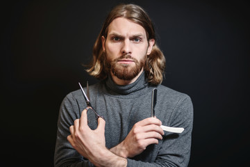 Portrait of hairdresser at black background isolated. Portrait of bearded man. Barber with scissors and straight razor, barber shop. Vintage barbershop, shaving. Beard macho man. Brutal guy.