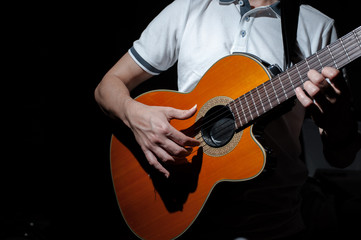 Fototapeta na wymiar Man playing an acoustic guitar on a dark background. Playing guitar
