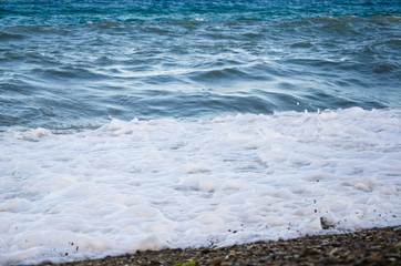 Colorful seascape, white foam of wave on beach close up