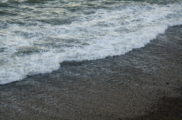 Seascape, view of beach and sea foam at sunset