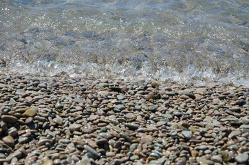 Background of seashore, pebble beach and transparent sea close up