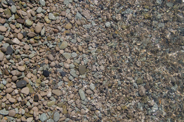 Background of seashore, pebble beach and transparent sea top view