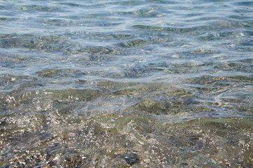 Abstract sea background, view on ripple surface of water, stone bottom underwater