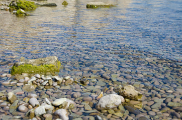 Background of seashore, pebble beach and blue water of sea close up
